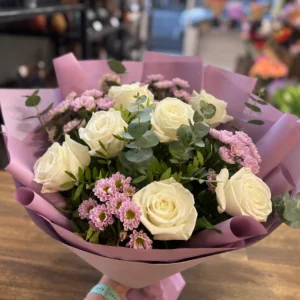 Mauve wrapped bouquet with white roses, soft pink chrysanthemums, eucalyptus and fresh greenery