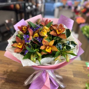 Warm autumn bouquet with bronze cymbidium orchids, orange alstroemeria, purple statice and glossy greenery