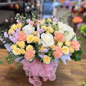 Pastel flower basket with peach carnations, cream roses, spray roses, hydrangea and lilac flowers