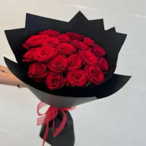 Bouquet of red roses wrapped in black paper with a red ribbon