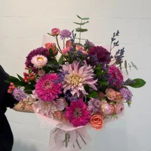 Large bouquet of magenta and purple flowers with peach roses and greenery